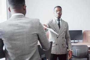 een project bespreken. twee zwarte zakenmensen in formele kleding die iets bespreken terwijl een van hen een papier wijst foto