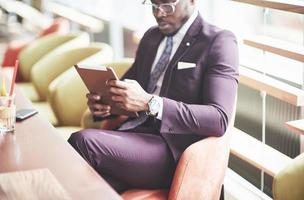 een mooie Afro-Amerikaanse zakenman leest in een café. foto