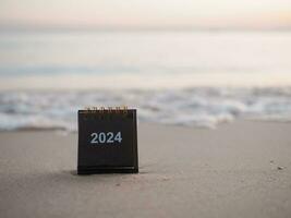 dichtbij omhoog 2024 bureau kalender Aan de strand in de zonsondergang tijd. oplossing, doel, actie, planning, en beheren naar succes bedrijf. foto