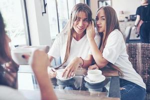 de drie beste vriendinnen kwamen samen om koffie te drinken en te roddelen. meiden die plezier hebben en lachen foto