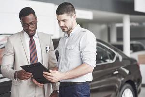 een Afro-Amerikaan met een adviseur bij een autodealer kiest een auto. goed koopje.