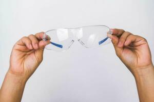 hand- Holding veiligheid bril, persoonlijk beschermend apparatuur. beschermend bril in hand- geïsoleerd Aan wit achtergrond. foto