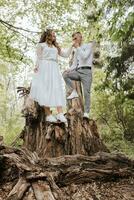 bruiloft wandelen in de Woud. de bruidegom houdt de bruid hand- en ze staan Aan een groot boom stomp. verticaal foto