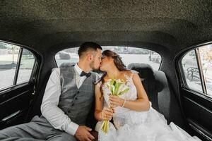 jong gelukkig bruid en bruidegom in hun auto verheugen en kus na de bruiloft ceremonie foto