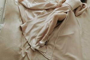 bijgesneden foto van een vrouw aan het liegen Aan een bed in een avond jurk gemaakt van satijn kleding stof