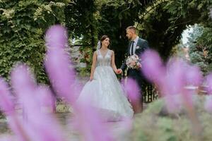 een bruiloft paar is genieten van de het beste dag van hun leven tegen de achtergrond van groen bladeren in de park. portret van bruiden in liefde in natuur foto