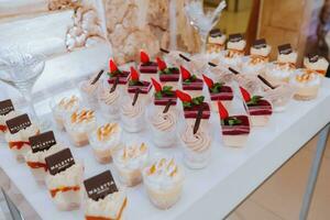 een heerlijk bruiloft. wit taart versierd met bloemen. snoep bar voor een banket. viering concept. modieus desserts. tafel met snoepgoed, snoepjes. fruit foto