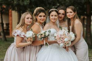 groep portret van de bruid en bruidsmeisjes hebben plezier. bruiloft. een bruid in een bruiloft jurk en haar vrienden in roze jurken Aan de bruiloft dag. elegant bruiloft in poeder kleur. concept van huwelijk. foto