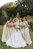 een groep van mooi Dames in bij elkaar passen jurken zijn lachend, vieren, en hebben pret samen. vrienden van de bruid in roze jurken vieren de bruiloft samen met de bruid foto