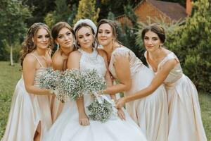 een groep van mooi Dames in bij elkaar passen jurken zijn lachend, vieren, en hebben pret samen. vrienden van de bruid in roze jurken vieren de bruiloft samen met de bruid foto