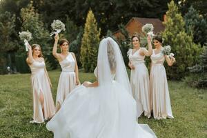 een groep van mooi Dames in bij elkaar passen jurken zijn lachend, vieren, en hebben pret samen. vrienden van de bruid in roze jurken vieren de bruiloft samen met de bruid foto