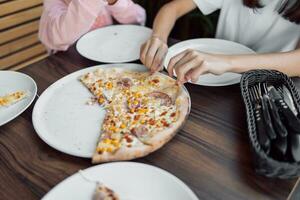 een overhead schot van een groep van niet geïdentificeerd mensen grijpen een plak van hawaiiaans pizza foto