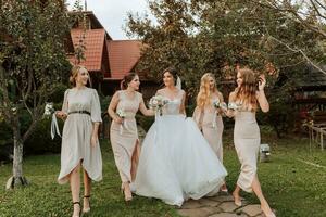 groep van mooi Dames in identiek jurken lachend, vieren en hebben pret samen. vrienden van de bruid vieren de bruiloft samen met de bruid in natuur foto