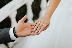 detailopname van bruidegom hand- Holding bruid wirst inschrijving foto