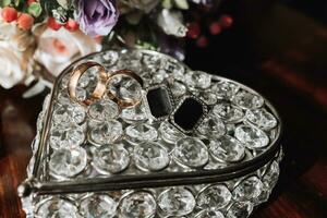 bruidegom accessoires in de ochtend. goud bruiloft ringen en zwart overhemd manchetknopen foto