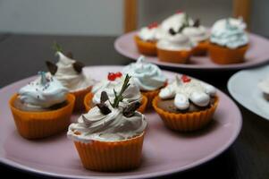 cupcakes versierd met geslagen room en chocola Aan een roze bord foto