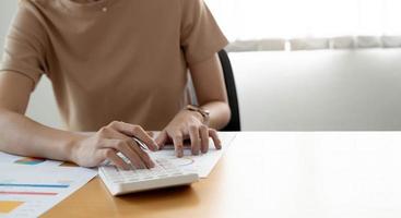 close-up vrouw die rekenmachine en laptop gebruikt om wiskunde te financieren op houten bureau in kantoor en zakelijke achtergrond, belasting, boekhouding, statistiek en analytisch onderzoeksconcept foto