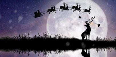 silhouet van de kerstman die over de volle maan vliegt. foto