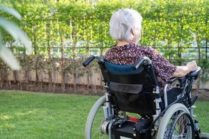 Aziatische senior vrouw patiënt op elektronische rolstoel in park. foto