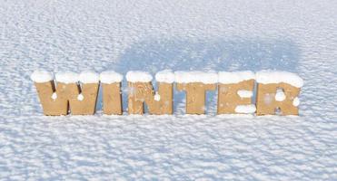 houten letters met het woord winter op besneeuwde grond foto