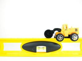 speelgoed druk weg auto met gebouw niveau op witte achtergrond, engineering bouwconcept foto