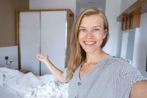 gelukkig vrouw tonen haar hotel kamer nemen selfie foto