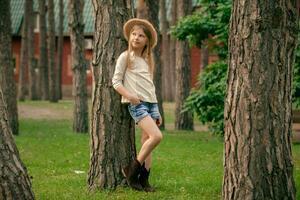 dromerig preteen meisje leunend tegen hoog boom in groen binnenplaats van land huis foto