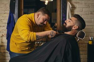 cliënt met groot zwart baard gedurende baard scheren in kapper winkel foto