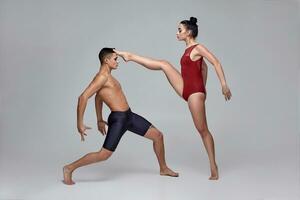 de paar van een atletisch modern ballet dansers zijn poseren tegen een grijs studio achtergrond. foto