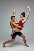 de paar van een atletisch modern ballet dansers zijn poseren tegen een grijs studio achtergrond. foto