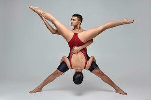 de paar van een atletisch modern ballet dansers zijn poseren tegen een grijs studio achtergrond. foto