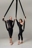 mooi meisje en een atletisch Mens in een zwart sport pakken zijn het uitvoeren van een acrobatisch elementen in een studio. foto