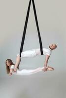 mooi meisje en een atletisch Mens in een wit sport pakken zijn het uitvoeren van een acrobatisch elementen in een studio. foto