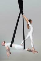 mooi meisje en een atletisch Mens in een wit sport pakken zijn het uitvoeren van een acrobatisch elementen in een studio. foto