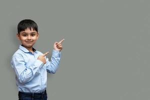 lachende gelukkige jongen wijzende vinger weg naar kopieerruimte geïsoleerd over effen achtergrond foto
