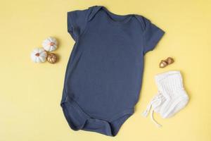 baby clobodysuit-model met pompoenen op gele achtergrond voor uw tekst of logo in het herfstseizoen