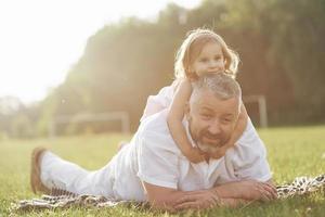 een schattig klein meisje brengt tijd door met haar geliefde grootvader in het park foto
