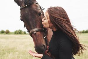 een gelukkig meisje communiceert met haar favoriete paard. het meisje houdt van dieren en paardrijden