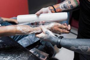 close-up tattoo-machine. meester in zwarte steriele handschoenen die er een foto bij de hand mee maakt in de salon