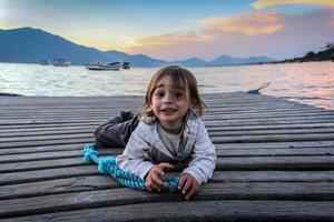 portret van een kleine jongen die naar de camera kijkt, liggend op een pier foto