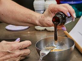 chef-kok handen gieten siroop in kom met mengsel voor huis Koken foto