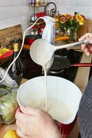 eigengemaakt keuken gastvrouw gieten pannenkoek mengen van pollepel in lekt kom foto