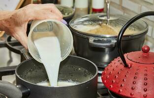 chef-kok handen gieten melk in een kom met mengsel voor Koken Bij huis keuken foto