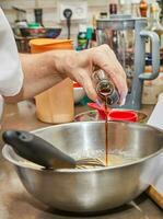 detailopname beeld van een chef-kok handen gieten zoet siroop in een kom met een mengsel, presentatie van de werkwijze van huis Koken en bakken. de handen zijn vakkundig voorbereidingen treffen een heerlijk recept foto