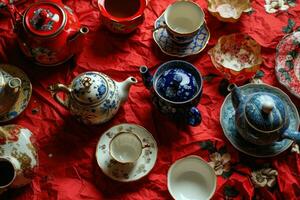 ai gegenereerd een arrangement van thee cups en theepotten Aan rood papier foto