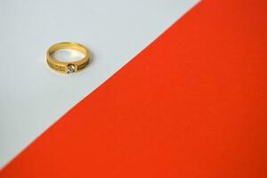 dichtbij omhoog gouden ring met diamant Aan diagonaal wit en oranje achtergrond foto