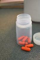 medisch pil capsule en fles met mok of glas van water Aan tafel werkruimte foto