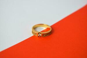 dichtbij omhoog gouden ring met diamant Aan diagonaal wit en oranje achtergrond foto