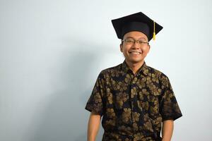 expressief van volwassen Indonesië mannetje slijtage batik, toga kop of diploma uitreiking hoed en bril geïsoleerd Aan wit achtergrond, uitdrukkingen van portret diploma uitreiking foto