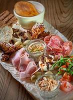 antipasto, antipasti - bord met paté, prosciutto, brood, kaas, salami, ham, worst, varkensvlees, hummus, mosterd, tomaat foto